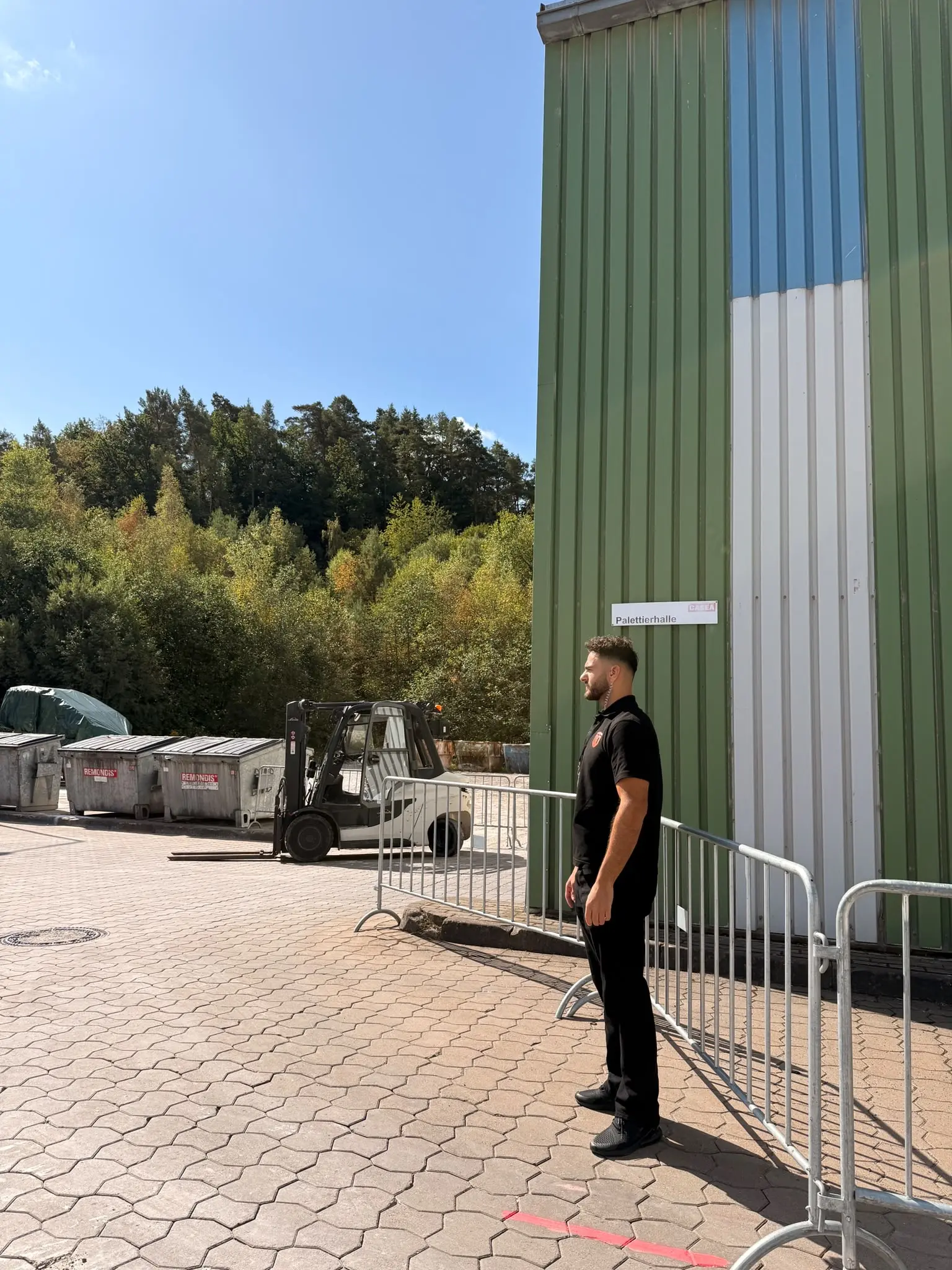 GuardDrive-Mitarbeiter im schwarzen Firmenpolo vor einer Gewerbehalle; Originalaufnahme aus dem Team