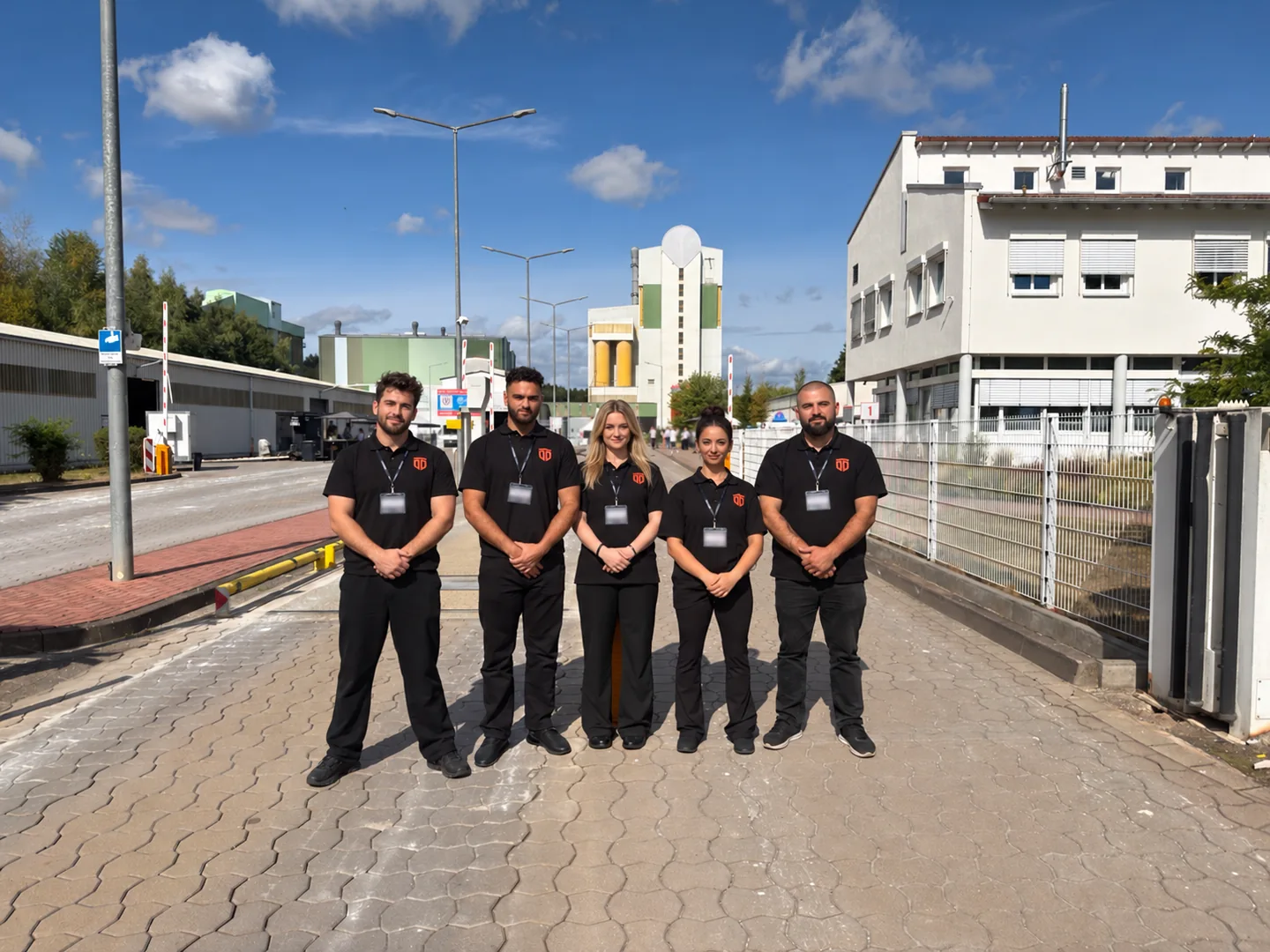GuardDrive-Team in schwarzen Firmenpolos vor einem Betriebsgelände; Gesichter zum Schutz der Privatsphäre digital verändert.